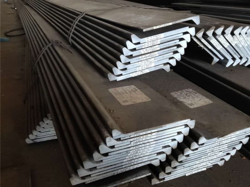 Shipyard workers welding L-shaped steel on a large vessel hull