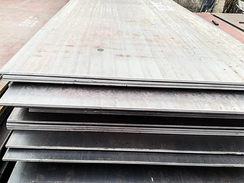 Worker bending a thick steel plate with a hydraulic press in a shipyard