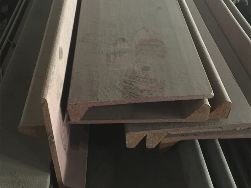 Bulb flat steel stored on wooden racks under covered shelter at shipyard